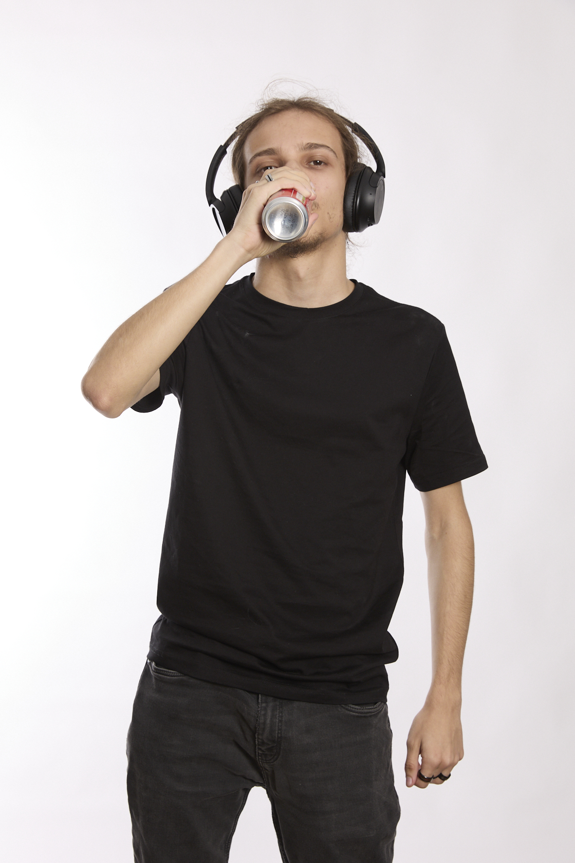 <p>jeune homme qui boit une canette de boisson sucrée en écoutant de la musique</p>
